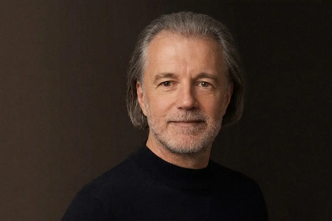 Alexander Renner im dunklen Pullover vor dunkelbraunem Studiohintergrund